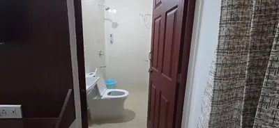 a bathroom with a toilet and a red door at PPH Living Arvind Inn in Coimbatore