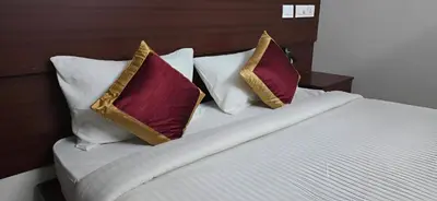 a bedroom with a bed with three pillows on it at PPH Living Arvind Inn in Coimbatore
