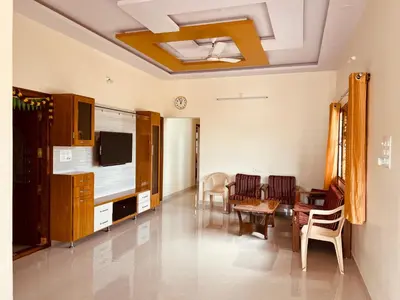 a living room with a tv and a table and chairs at A B House in Kollegālam