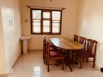 a dining room with a wooden table and chairs at A B House in Kollegālam