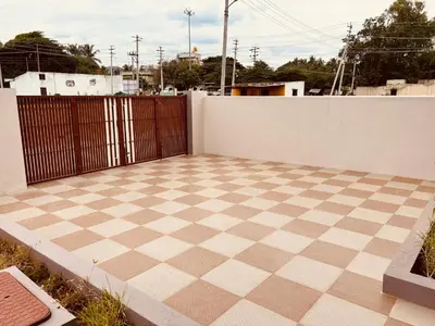a patio with a checkered floor in front of a fence at A B House in Kollegālam