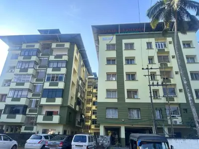 a tall building with cars parked in front of it at Gokulam By Upasana in Guruvāyūr