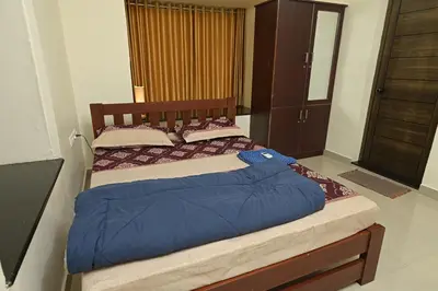 a bedroom with a bed with a blue comforter at Gokulam By Upasana in Guruvāyūr
