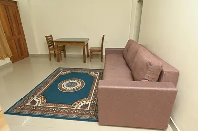 a brown couch in a living room with a table at Gokulam By Upasana in Guruvāyūr