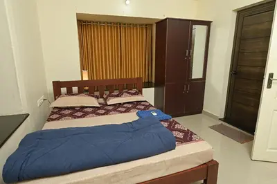 a bedroom with a large bed with a wooden headboard at Gokulam By Upasana in Guruvāyūr