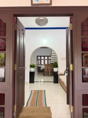 an open door into a living room with a table at Dream House Near IIM Kozhikode & NIT Calicut in Kozhikode