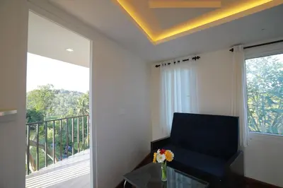a living room with a chair and a glass table at Blue Bell Resort in Periya