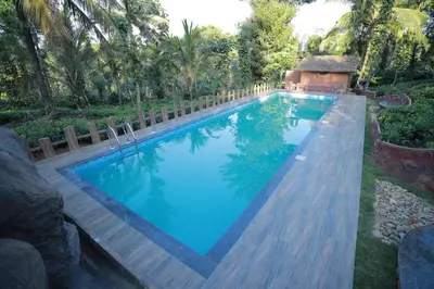a swimming pool in a backyard with a wooden fence at Blue Bell Resort in Periya