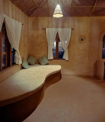 a bedroom with a bed in a room with windows at Nelli Mud Village in Thirunelli