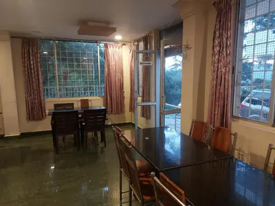 a dining room with a table and chairs and windows at GEM Stays in Ooty