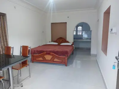 a bedroom with a bed and a table in it at GEM Stays in Ooty