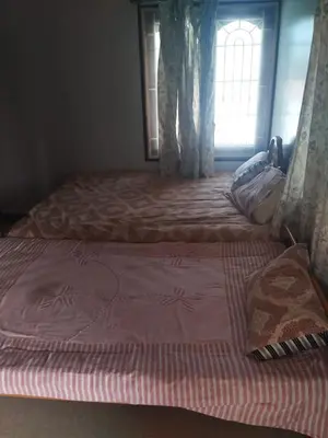 two beds in a bedroom with a window at Kumarasamy House in Tiruchengodu