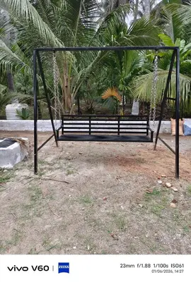 a swing bench in a park with palm trees at Limra Farm House in Pollāchi