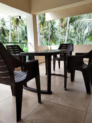 a table and chairs in a room with palm trees at Limra Farm House in Pollāchi