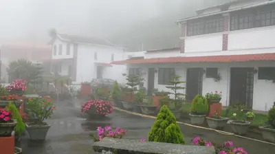 a rain soaked yard with houses and flowers in the rain at Trilan Cottages - Donnington Road in Kotagiri