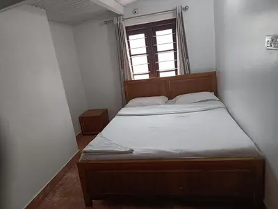 a bed in a small room with a window at Trilan Cottages - Donnington Road in Kotagiri