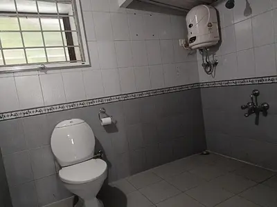 a bathroom with a white toilet and a window at Trilan Cottages - Donnington Road in Kotagiri