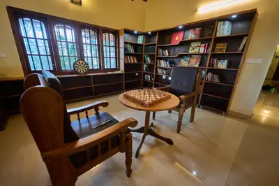a library with a table and chairs and book shelves at Ushasree Wayanad Premium Pool Resort by VOYE HOMES in Ambalavayal
