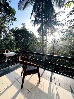 a bench sitting on a balcony looking out at the forest at Wild Castle Wayanad in Pulpally