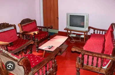 a living room with wooden chairs and a tv at Coorg Naladi holidays in Kakkabe