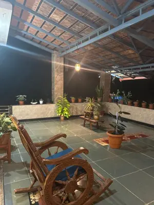 a room with a rocking chair and potted plants at Coorg Naladi holidays in Kakkabe