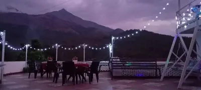 a patio with a table and chairs and lights at PADIKKAL BUNGLOW in Vayittiri