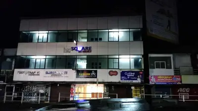 a building with a sign that says square at night at Misty Square Residency in Kalpetta