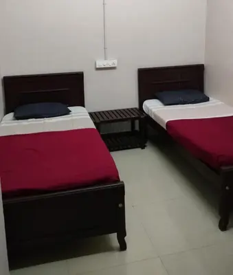 two beds sitting next to each other in a room at Misty Square Residency in Kalpetta