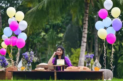 a woman sitting at a table with balloons at Avana Resort in Mettuppālaiyam