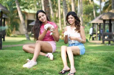 two young women sitting on the grass holding puppies at Avana Resort in Mettuppālaiyam