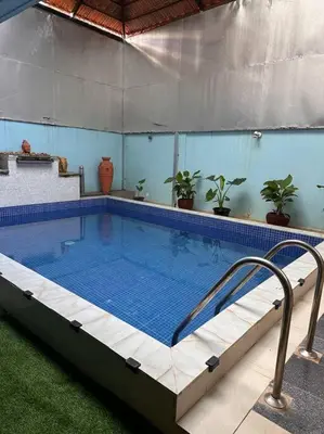 a large swimming pool in a building with plants at Aalayam, Villament & private pool in Mysore