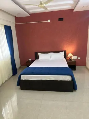 a bedroom with a large bed with a red wall at Aalayam, Villament & private pool in Mysore