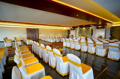 a room with rows of white chairs and tables at Hotel Yathin in Mysore