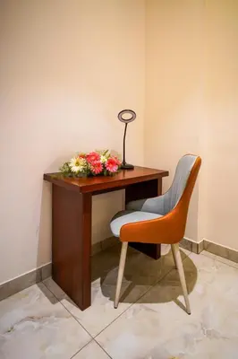 a desk with a vase of flowers and a lamp at Hotel Yathin in Mysore