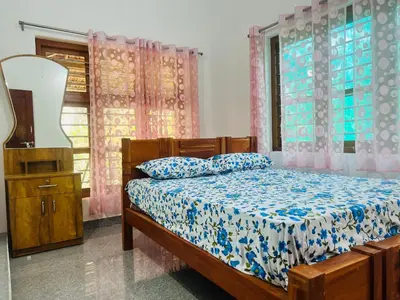 a bedroom with a bed and a dresser and windows at Misty Homes Stay in Napoklu