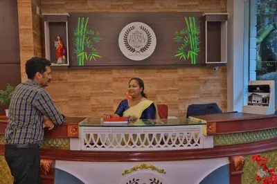 a man talking to a woman at a counter at Hydel Palace Athirappilly by Bestinn Leisure in Athirappilly