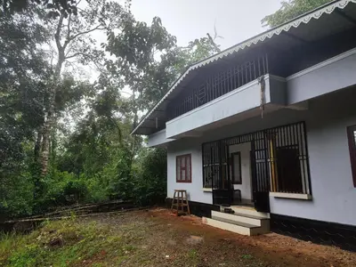 a white house with a stool in front of it at Brahmagiri Homestay Serviced Villa in Thirunelli