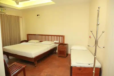 a bedroom with two beds and a chair in it at Wariyam Heritage in Trichūr
