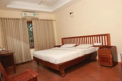 a bedroom with a bed with white sheets and a window at Wariyam Heritage in Trichūr
