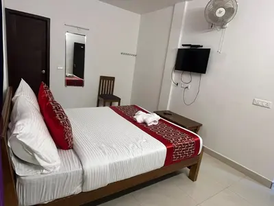 a bedroom with a bed with red pillows and a fan at BanyanThree in Kodaikānāl