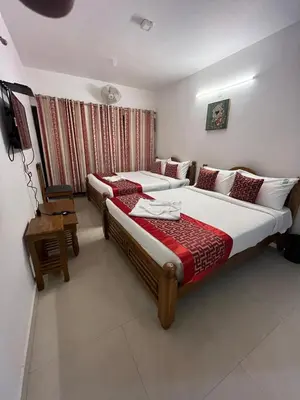 a hotel room with two beds and a television at BanyanThree in Kodaikānāl