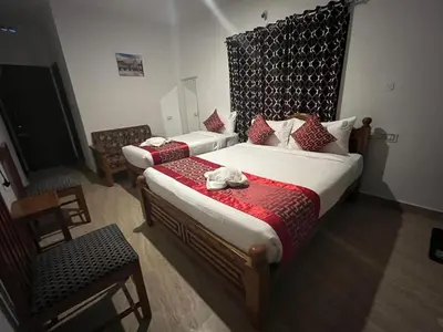 a hotel room with two beds and a chair at BanyanThree in Kodaikānāl
