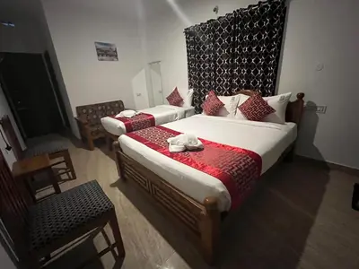 a hotel room with two beds and a chair at BanyanThree in Kodaikānāl