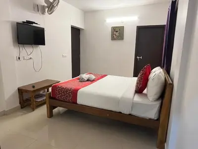 a bedroom with a bed and a tv on the wall at BanyanThree in Kodaikānāl