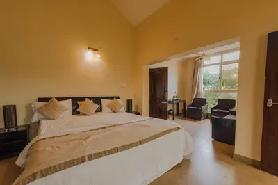 a bedroom with a large bed and a large window at Bota Royal in Kushālnagar