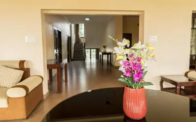 a red vase with flowers on a table in a living room at Bota Royal in Kushālnagar