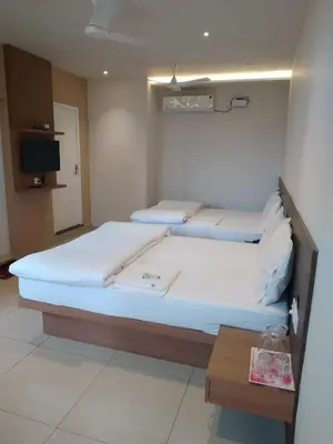 two beds in a room with a table and a tv at Sri bhavan residency in Palakkad