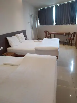 a hotel room with three beds and a table and chairs at Sri bhavan residency in Palakkad
