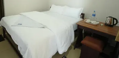 a hotel room with a white bed with a wooden table at Port View Residency PVR in Nedumbassery