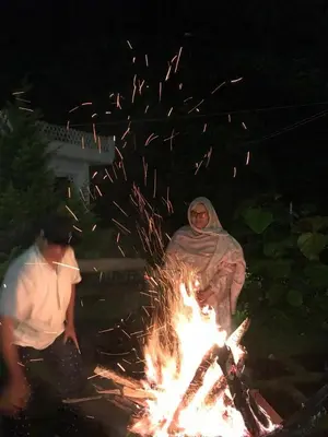 a woman sitting next to a bonfire at night at Padikkal Bungalow in Vayittiri